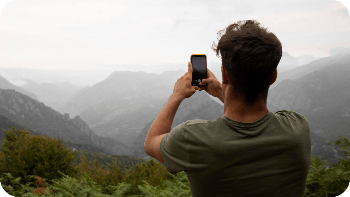 Young male traveler taking a photo of the mountains with his smartphone