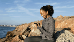 women sitting on a rock smiling and looking at her phone