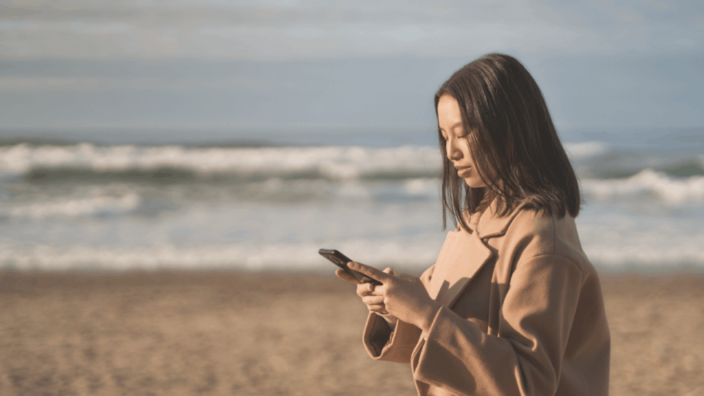 Women on the beach looking at her phone