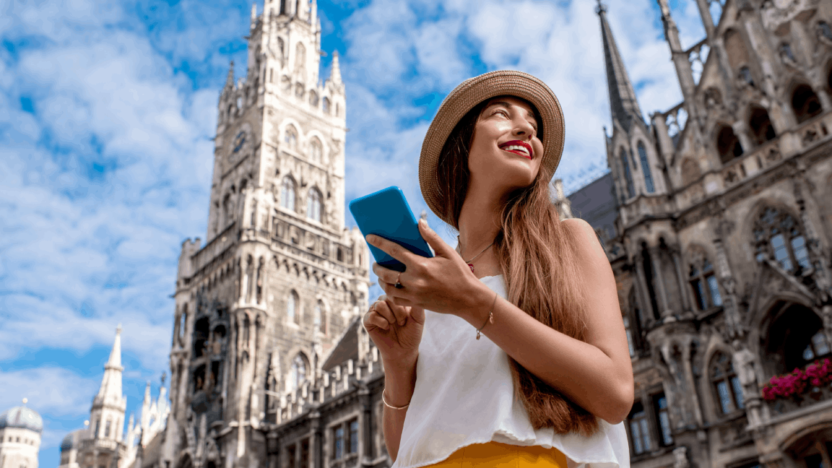 Young female tourist using her phone in the central square in front of hall building in Munich