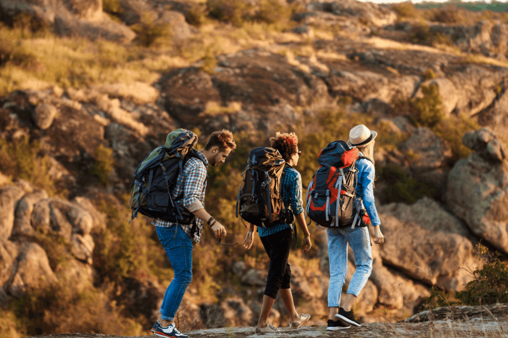 Young cheerful travelers with backpacks smiling, walking in canyon