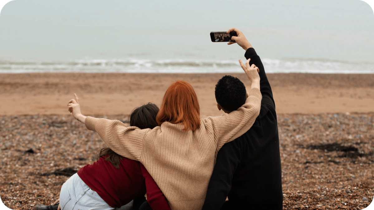 Three friends taking a selfie on a serene beach, capturing memories together.