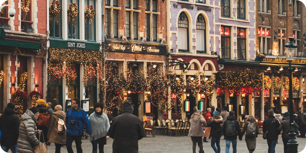 Charming holiday-decorated streets of Bruges, bustling with visitors enjoying festive lights and cozy cafes.