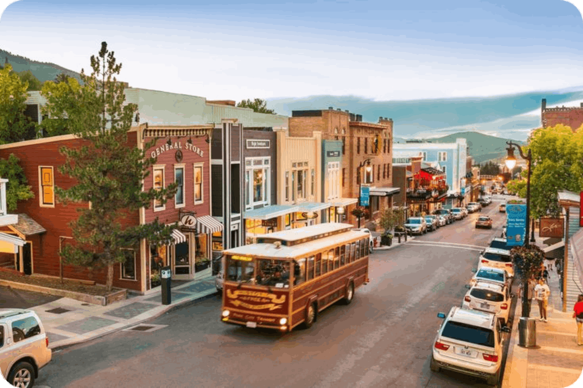  A charming Utah small-town street with colorful buildings, a vintage trolley, and a scenic mountain backdrop.